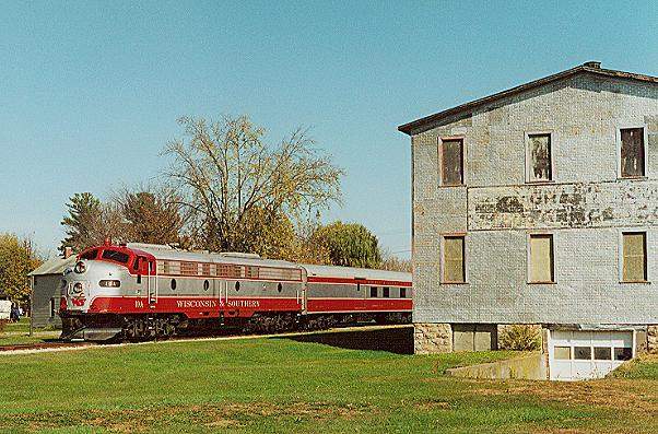 Photo of WSOR E-9A #10A leaves Boscobel, WI passing an old warehouse.