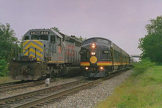 Photo of KCS Business Train passes a southbound freight in the hole at Siloam Springs, AR