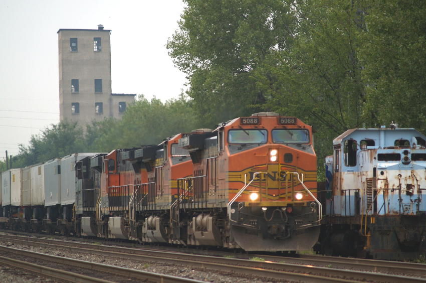 Photo of BNSF unit #5088 passes an old Alco center cab unit.