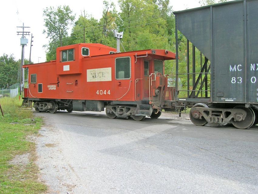 Photo of  Caboose on rear of cut of wood chip cars heading to McNeil generating station