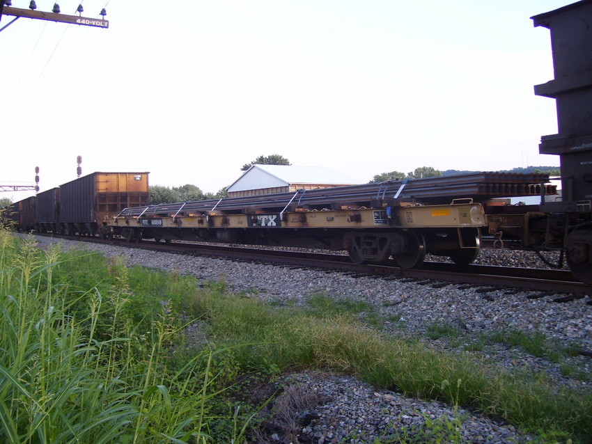 Photo of A TTX flat car with a few pieces of rail on it.