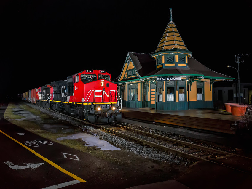Photo of Cn 2141 leads CN 393 past the restored Acton Vale, Quebec station